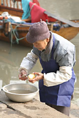 Old man peeling potatoes by Tongli canal